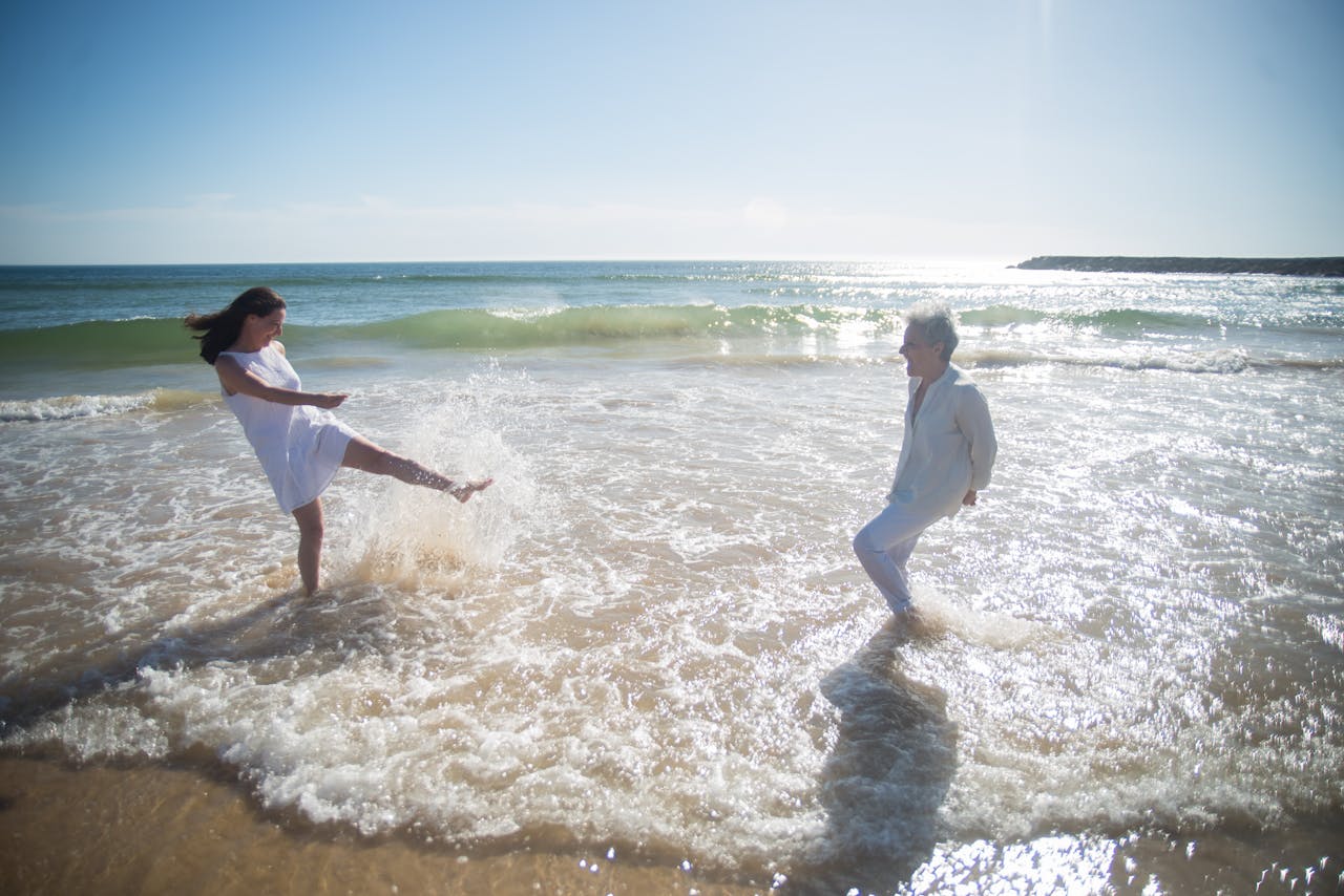 heros-img A joyful moment of a mother and daughter playing in the waves on a sunny beach in Portugal.